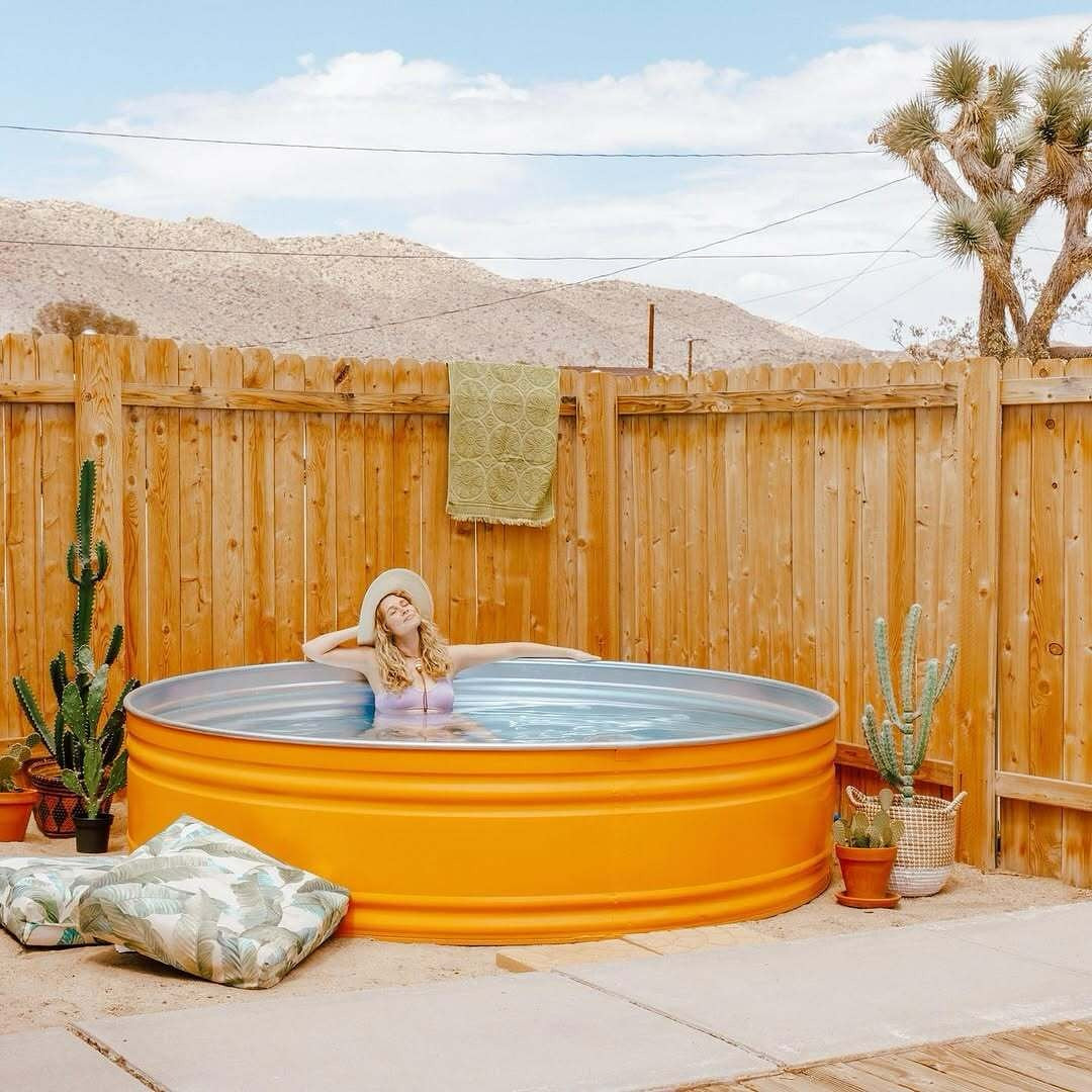 a girl in her backyard in a stock tank pool basking in the sunshine in a perth backyard 